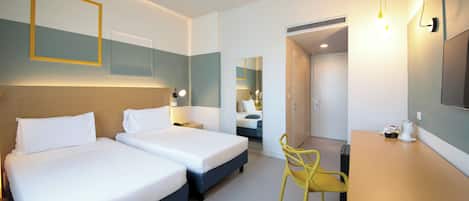 A hotel room with two beds, a desk, a chair, and a mirror.