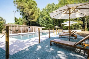 En säsongsöppen utomhuspool, parasoller och solstolar