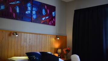 Ein Hotelzimmer mit einem hölzernen Kopfteil, einem Bett mit Kissen, einem Nachttisch mit Lampe und einem Bild an der Wand.