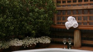 A hot tub with water lilies, a wooden fence, and a bench with towels. - Abisko Lodge (Methven)