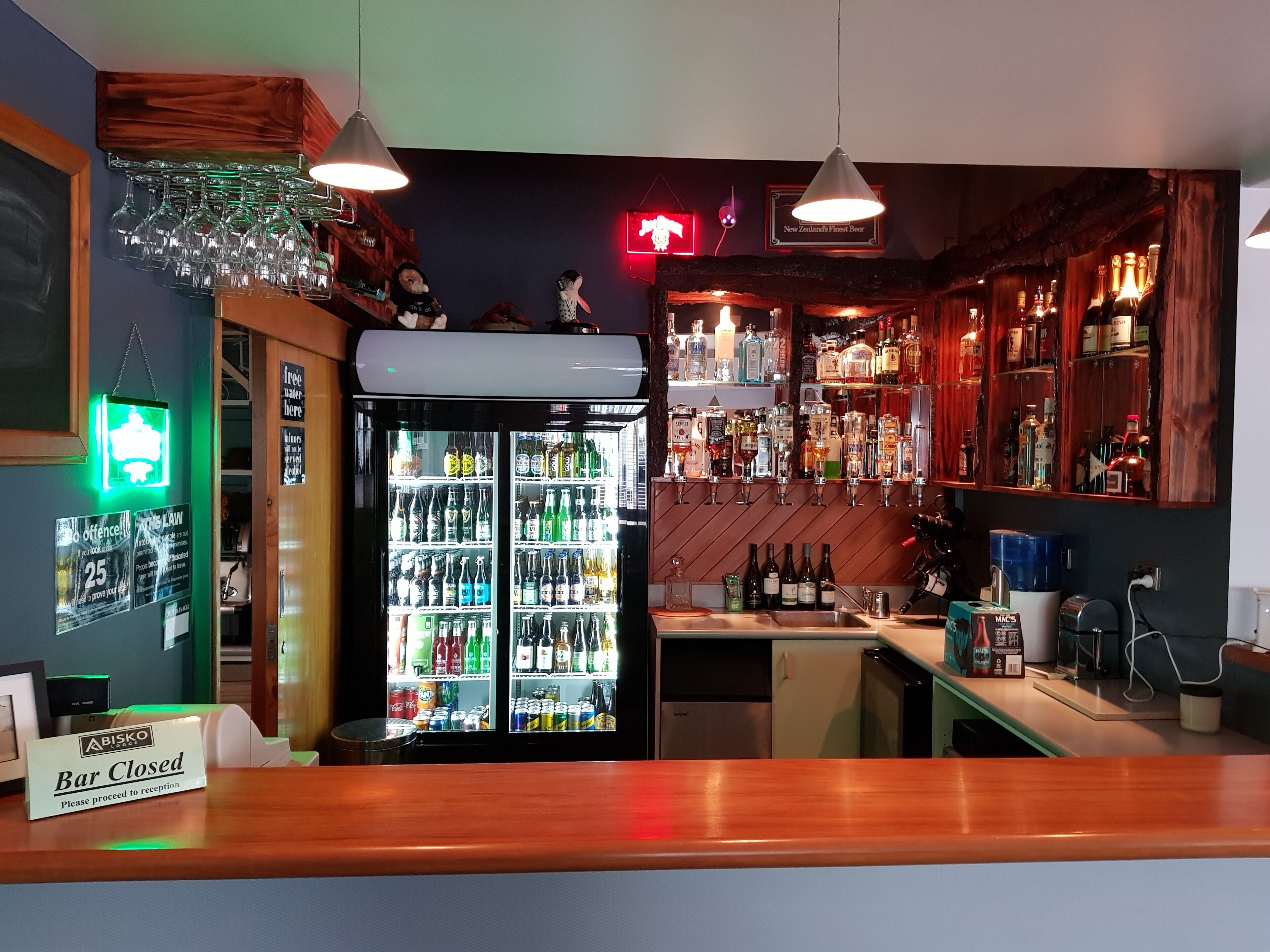 A bar area with a closed sign, a refrigerator stocked with beverages, and shelves with bottles.