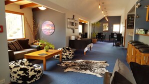 A modern living room with a blue carpet, a wooden coffee table, a sofa, and a cow-print bean bag. - Abisko Lodge (Methven)