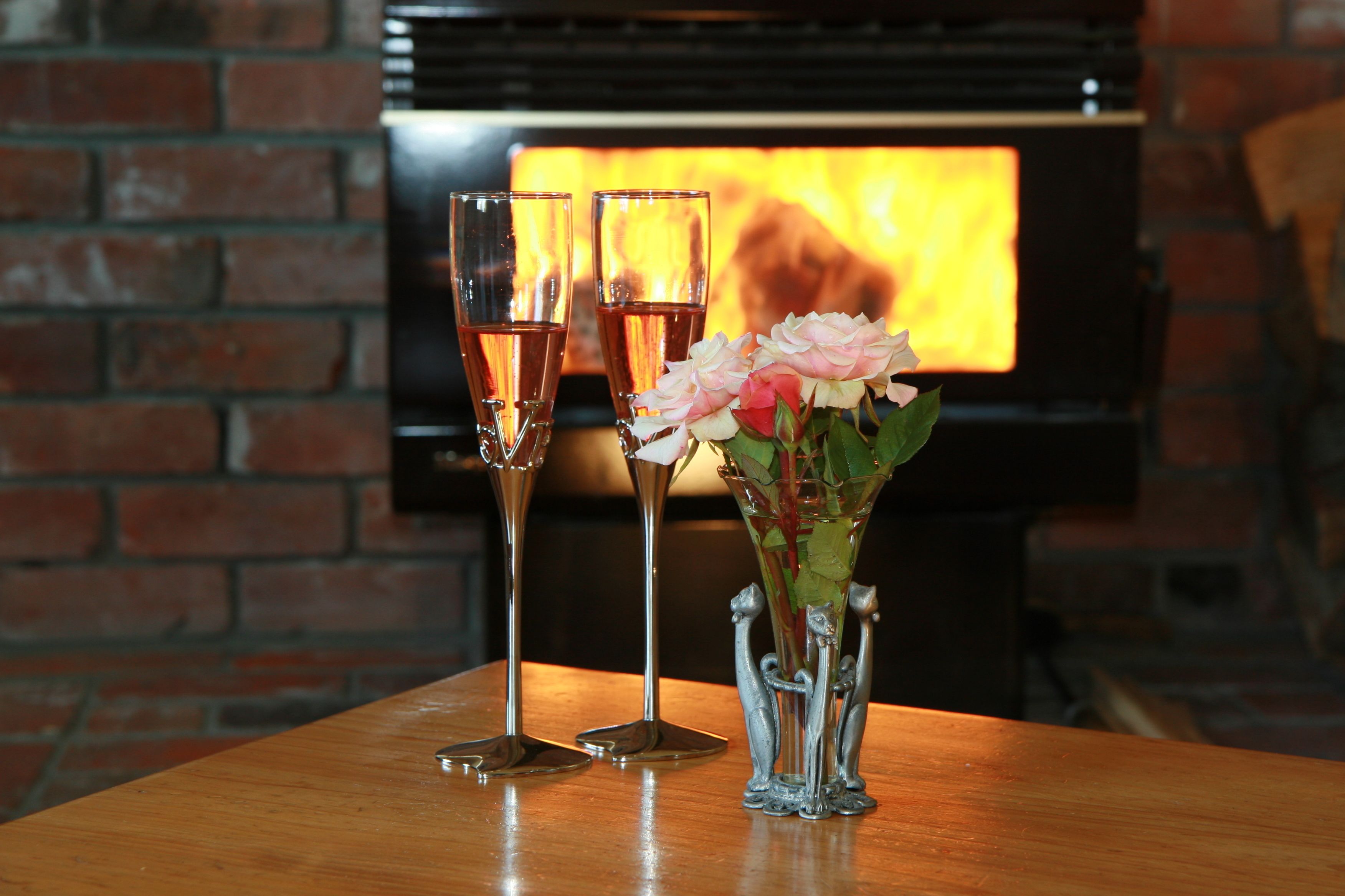 A table with two champagne flutes and a vase of flowers.