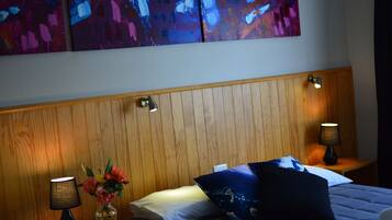 A hotel room with a wooden headboard, two bedside lamps, a vase with flowers, and a bed with pillows.