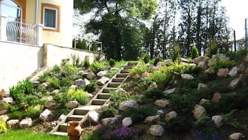 Um jardim bem cuidado com uma escadaria de pedra que leva a um edifício.