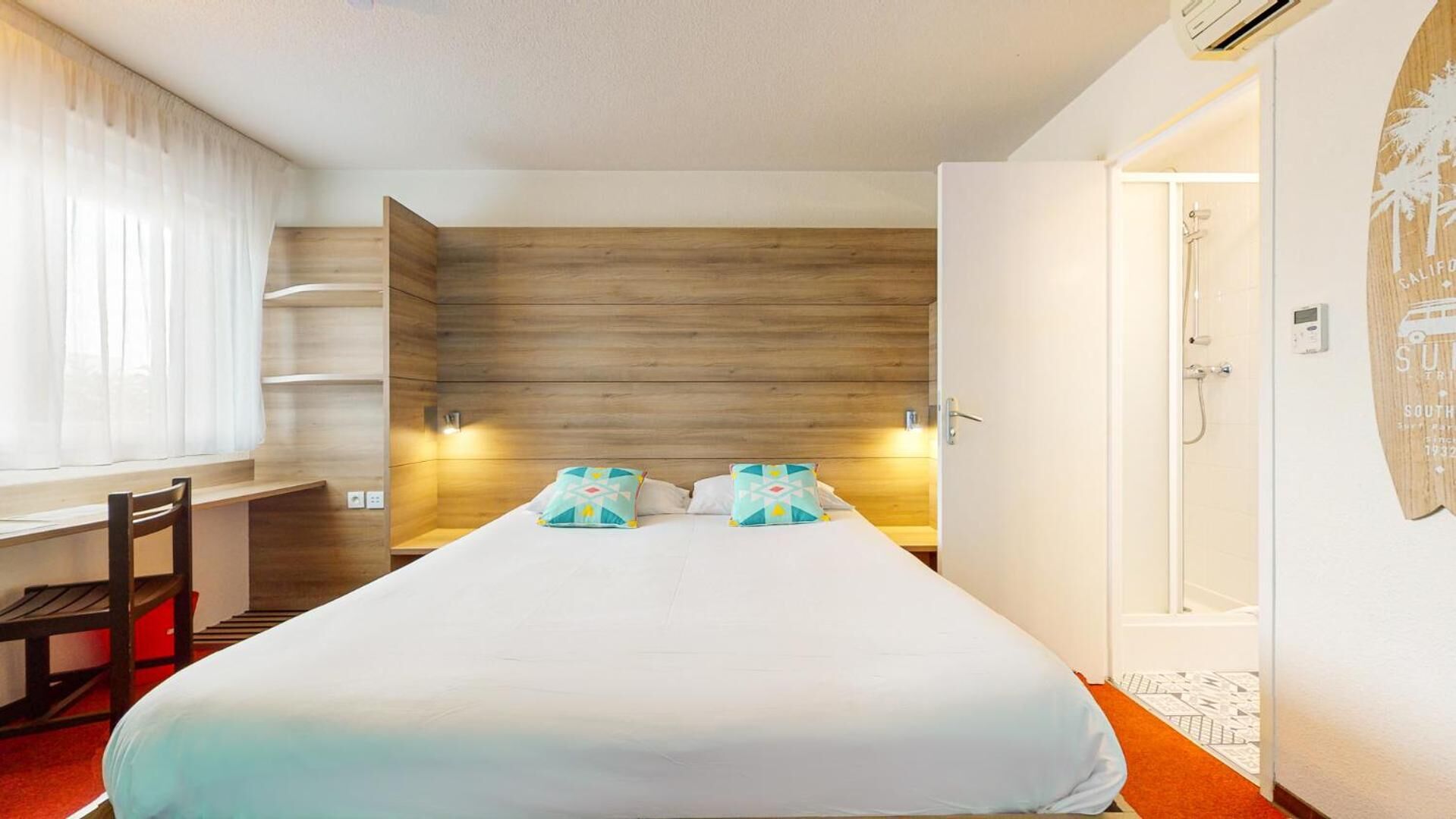Ein Hotelzimmer mit Bett, Schreibtisch und Dusche.