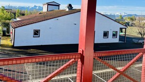 A white building with a red roof and a covered area with a red railing.