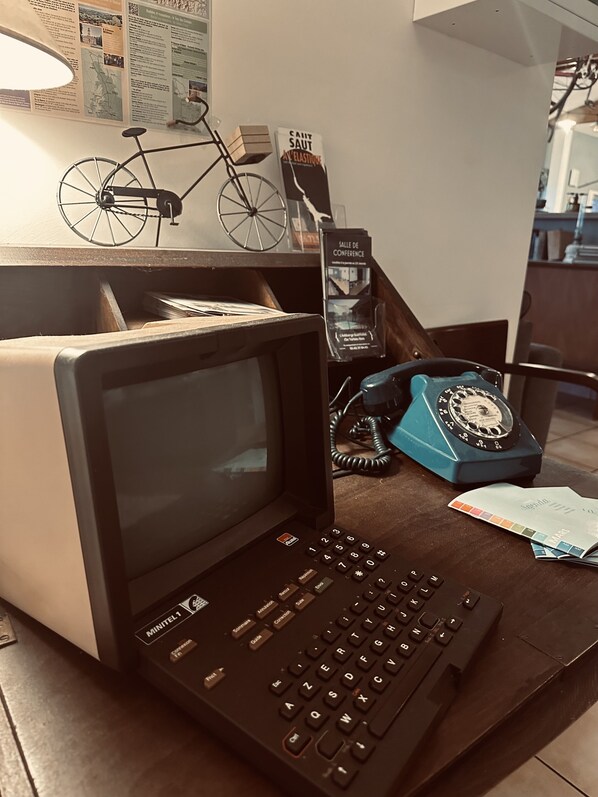 A vintage laptop with a keyboard, a rotary dial telephone, and a bicycle model on a desk.