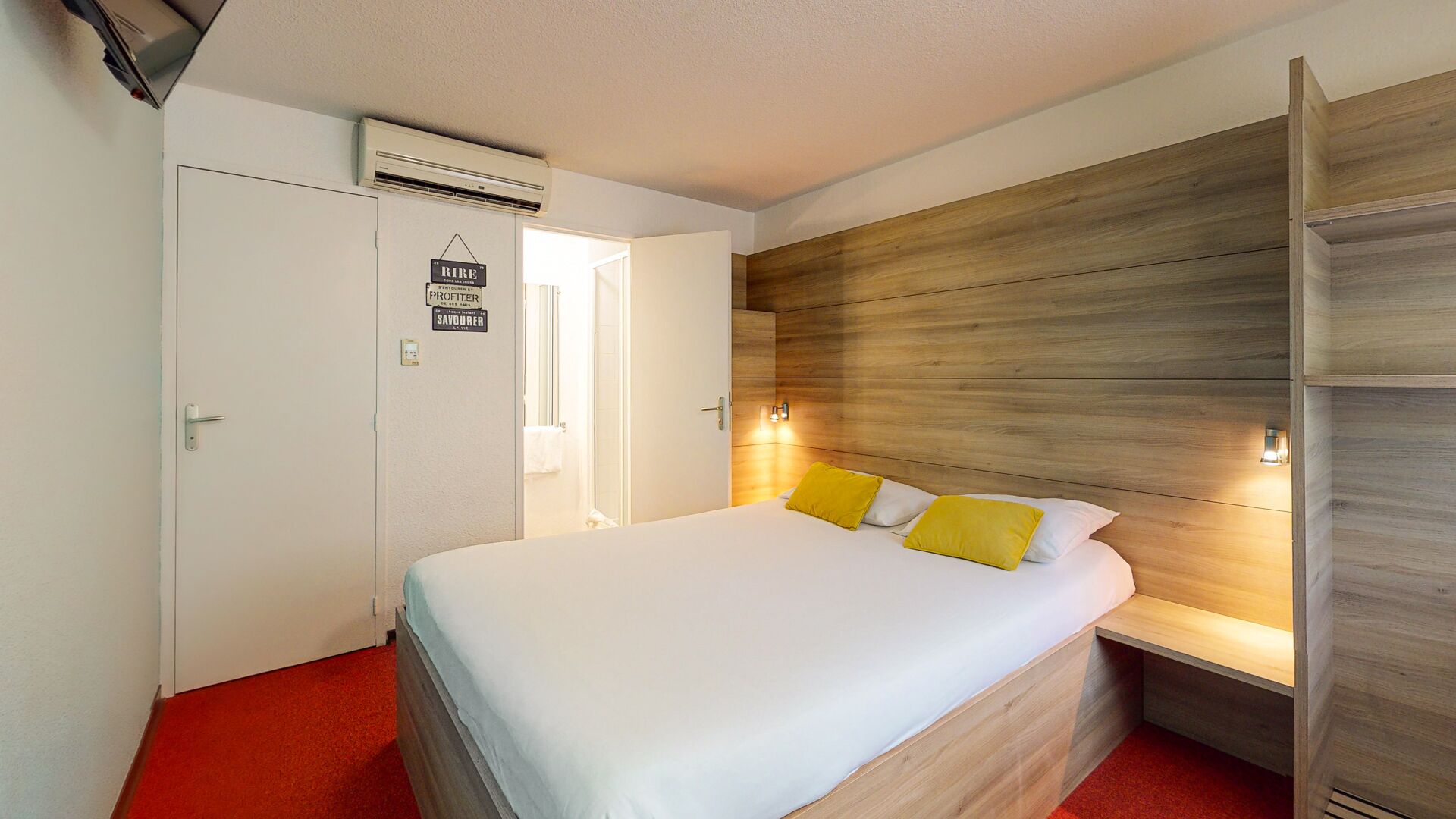 Una habitación de hotel con una cama, un armario y una alfombra roja.