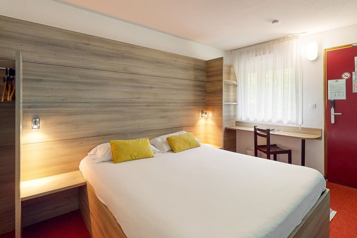 A hotel room with a bed, a desk, and a wardrobe.