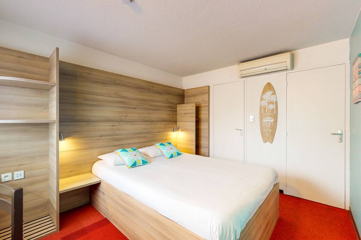 Una habitación de hotel con una cama, un escritorio y un armario.