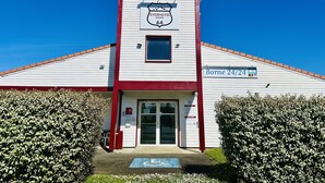 A hotel with a white facade, red trim, and a sign indicating it is a 24/24 accommodation.