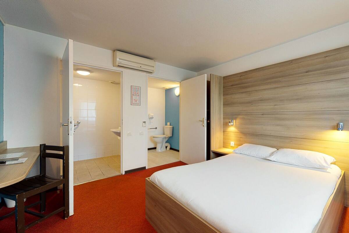 Una habitación de hotel con cama, escritorio y baño.