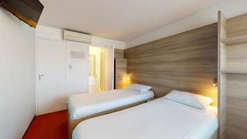 Ein Hotelzimmer mit zwei Einzelbetten, einem roten Teppich, einem hölzernen Kopfteil und einer Klimaanlage.