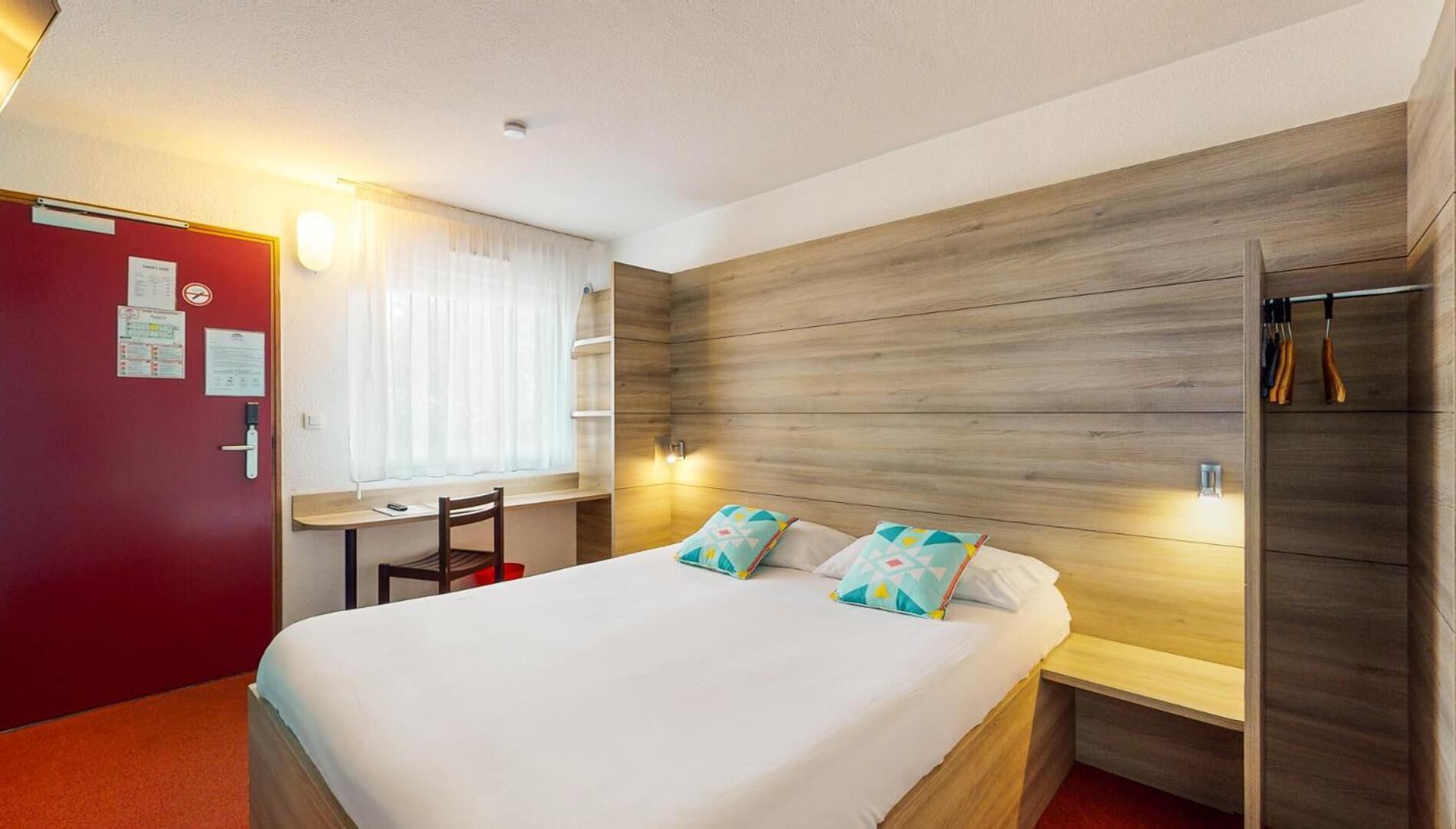Een hotelkamer met een bed, een bureau en een kledingkast.
