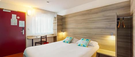 Una habitación de hotel con cama, escritorio y armario.