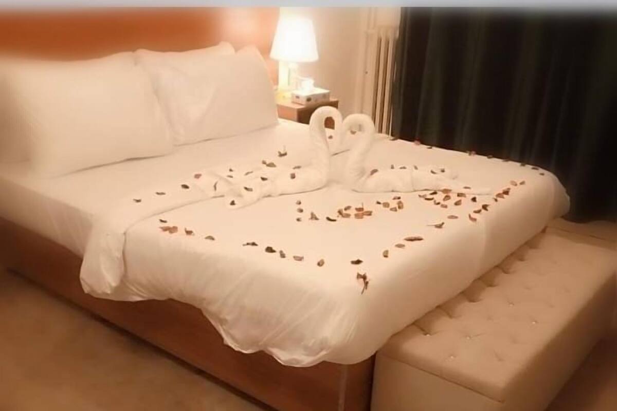 A neatly made bed with a white bedspread and a swan-shaped pillow.