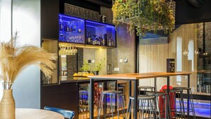 Un espace bar moderne avec un comptoir en bois, des tabourets et une plante suspendue.
