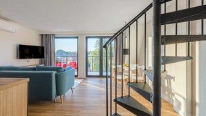 Un salon moderne avec un canapé, un téléviseur et un balcon doté d’un espace salon extérieur.