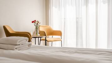 Et hotelværelse med seng, to stole, et lille bord og en vase med blomster.
