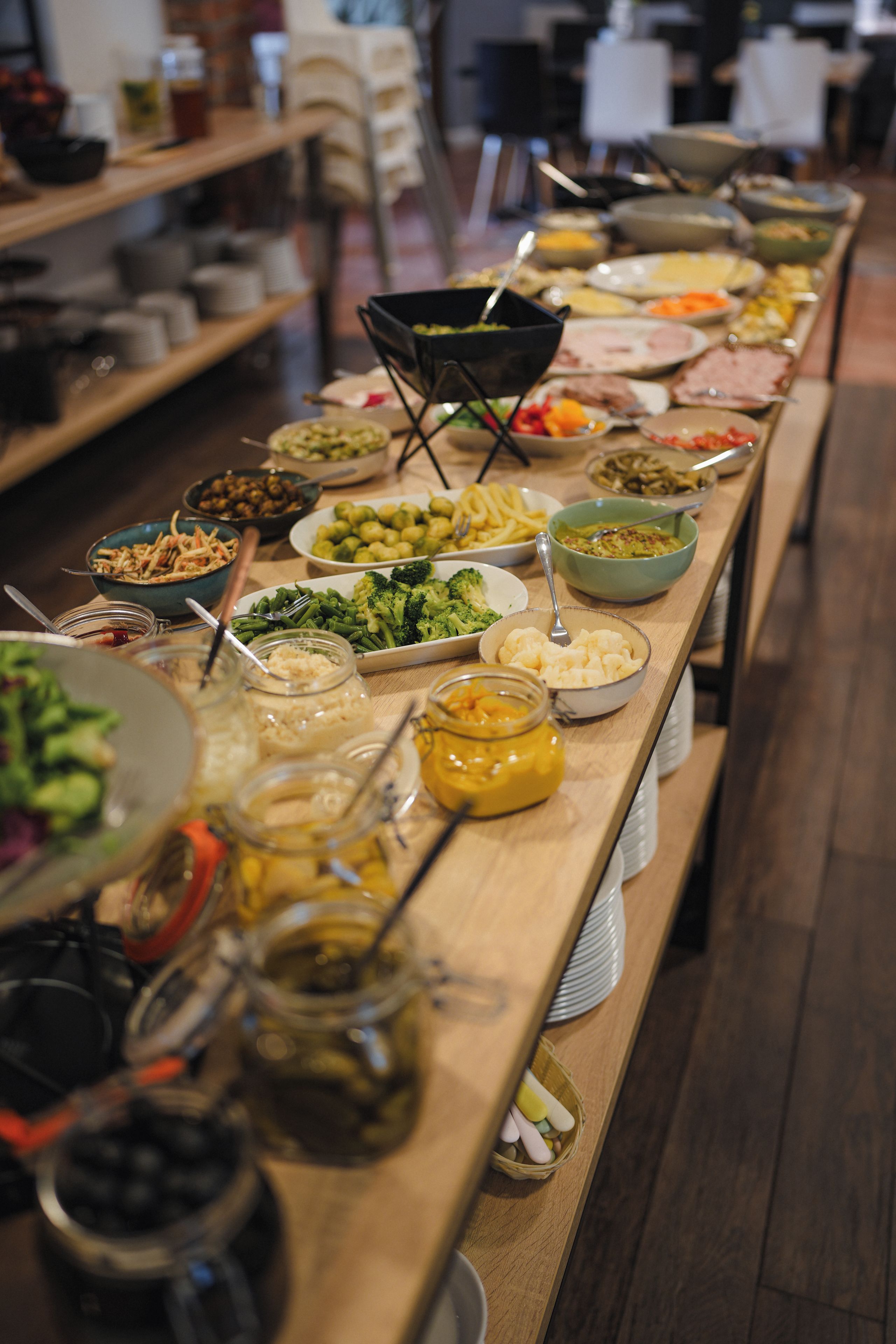 A buffet table with various dishes and condiments.