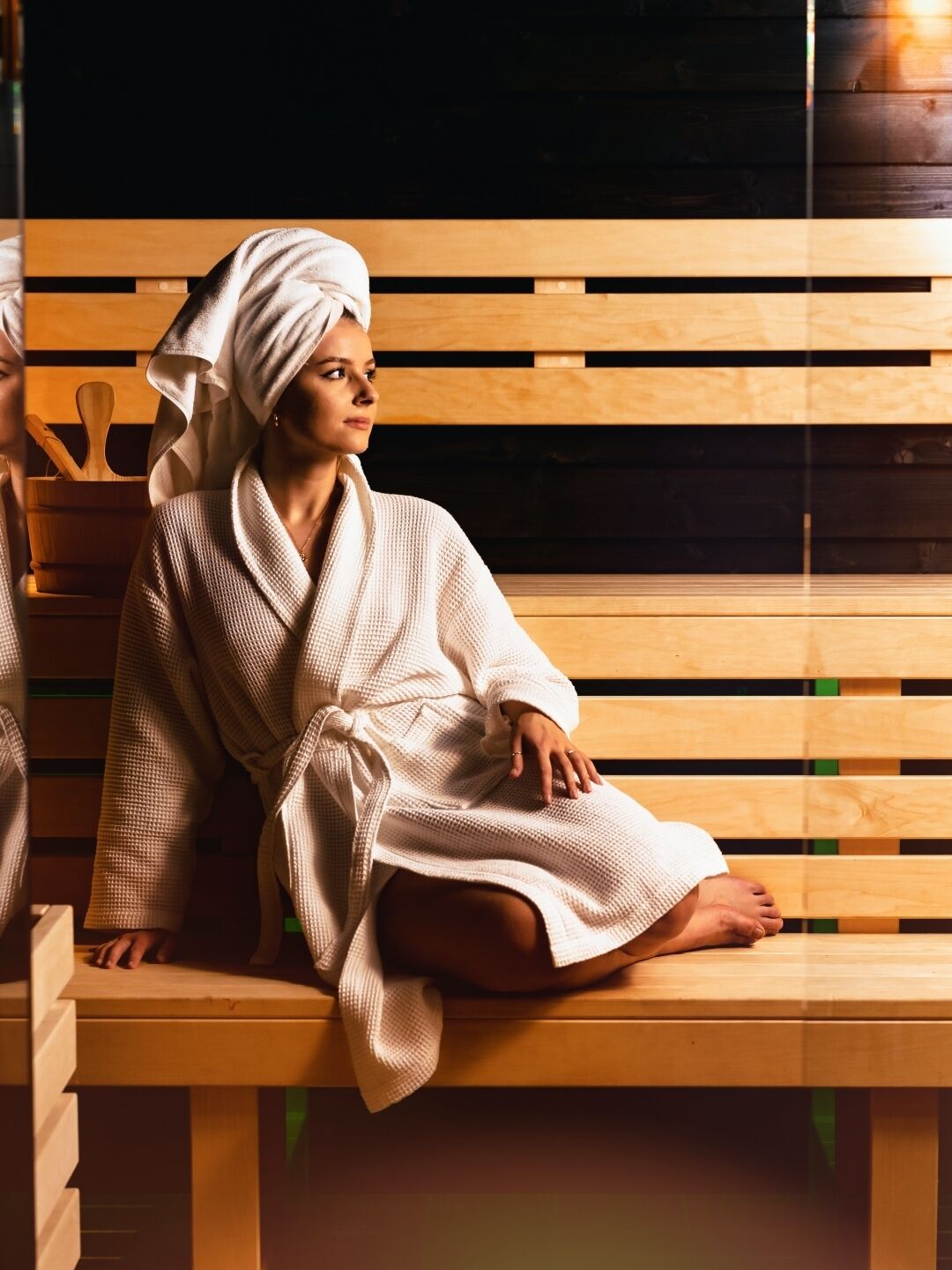 A person sitting on a wooden bench in a spa-like setting with wooden paneling in the background.
