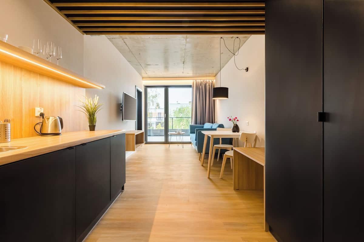 Une cuisine moderne avec un plan de travail en bois, des meubles noirs et une grande fenêtre.