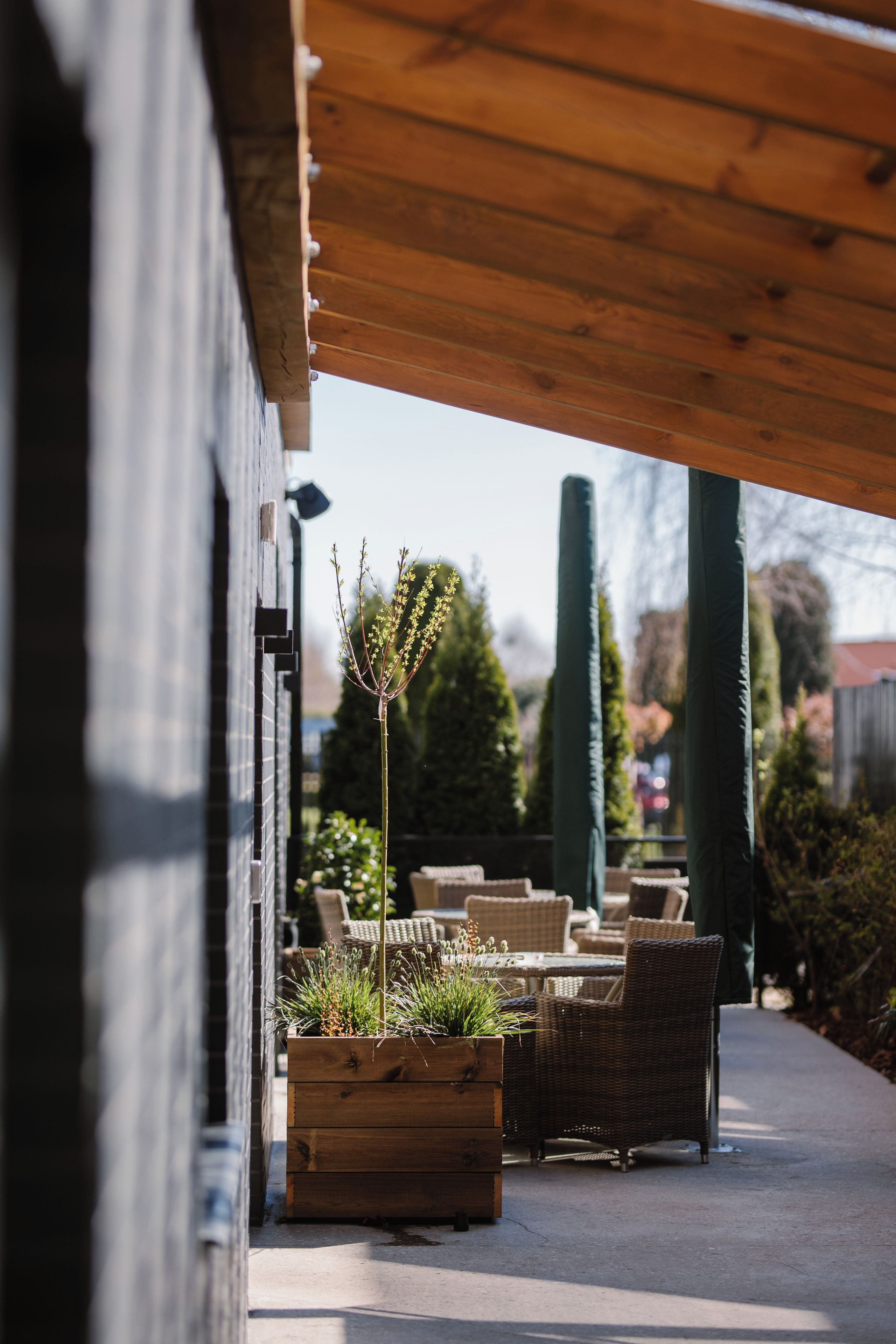 An outdoor seating area with wicker furniture and wooden planters.