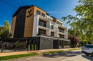 Um edifício moderno de vários andares com um destaque para o letreiro 'Villa Verde', com varandas e entrada para a garagem.