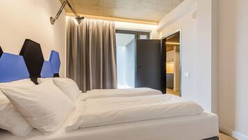 A modern hotel room with a double bed, a desk, and a large window with curtains.