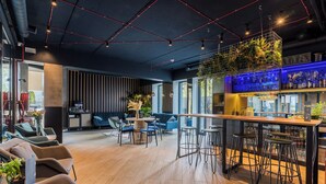 Un espace bar moderne avec un plancher en bois, des tabourets de bar et un coin salon comprenant des canapés et des fauteuils.