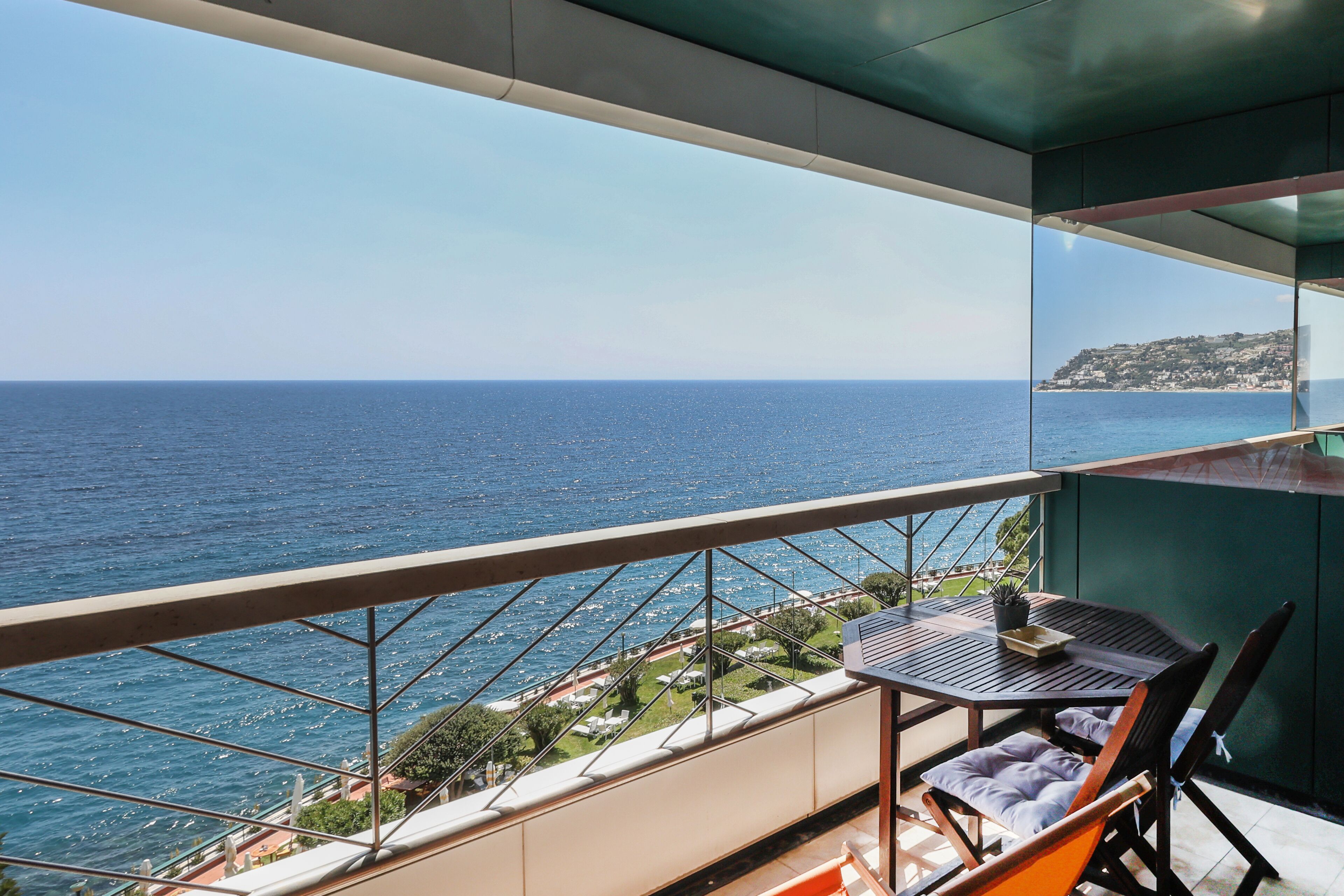 A balcony with a view of the sea and a distant town.