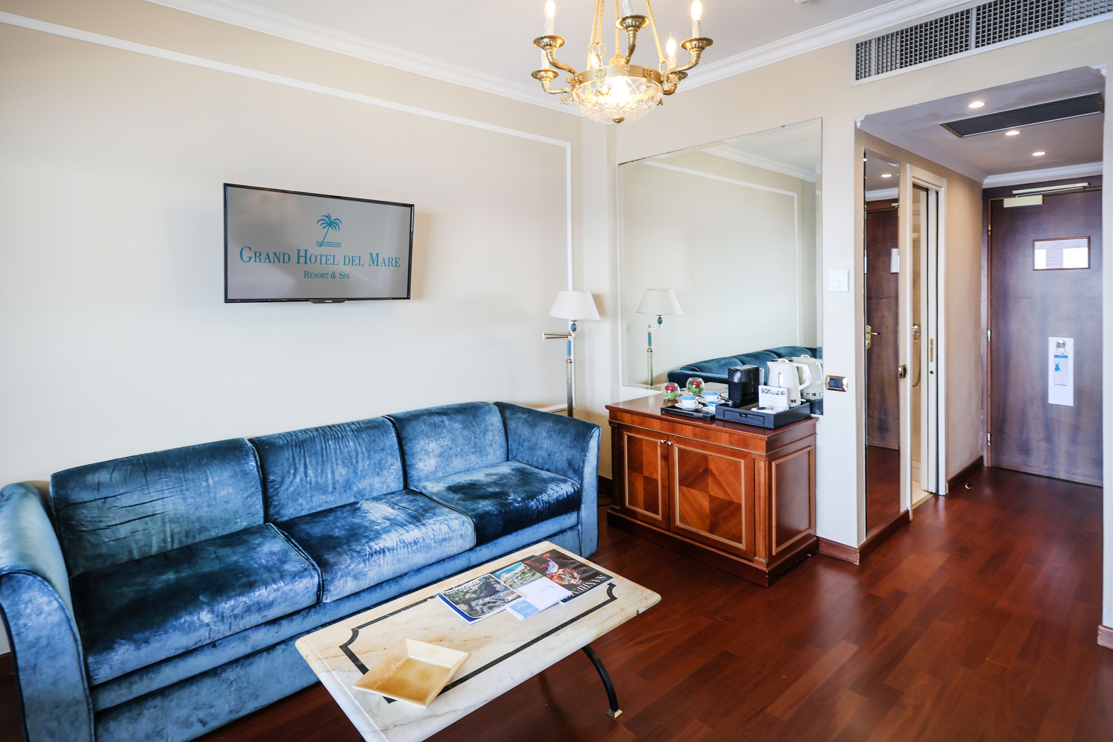 Una sala de estar con un sofá azul, una mesa de centro, un aparador de madera y un candelabro.