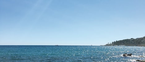 Playa privada, playa de arena negra, camastros y sombrillas