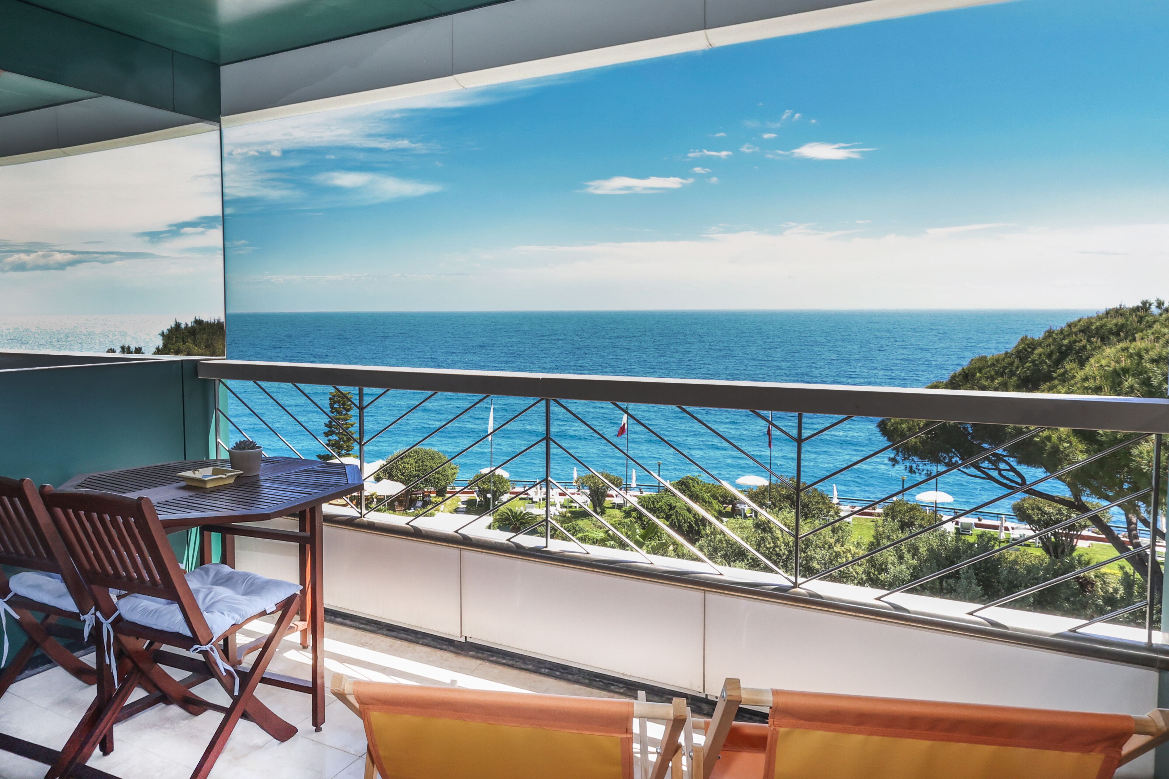 Un balcón con vistas al mar, una mesa y dos sillas.