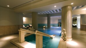 Une piscine agrémentée d’une balustrade en pierre, de colonnes et d’une statue.