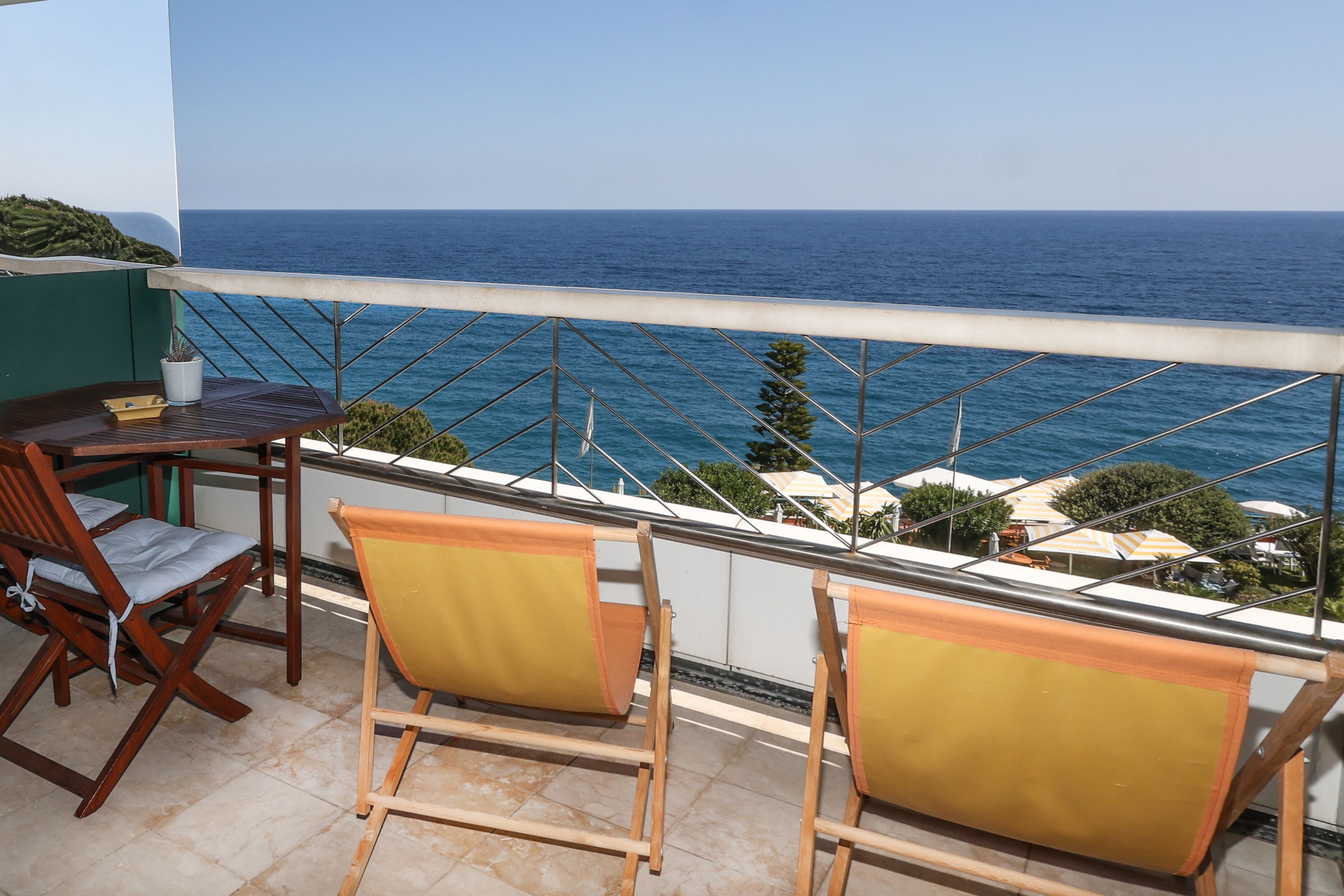 Un balcon avec une table et des chaises, donnant sur la mer.