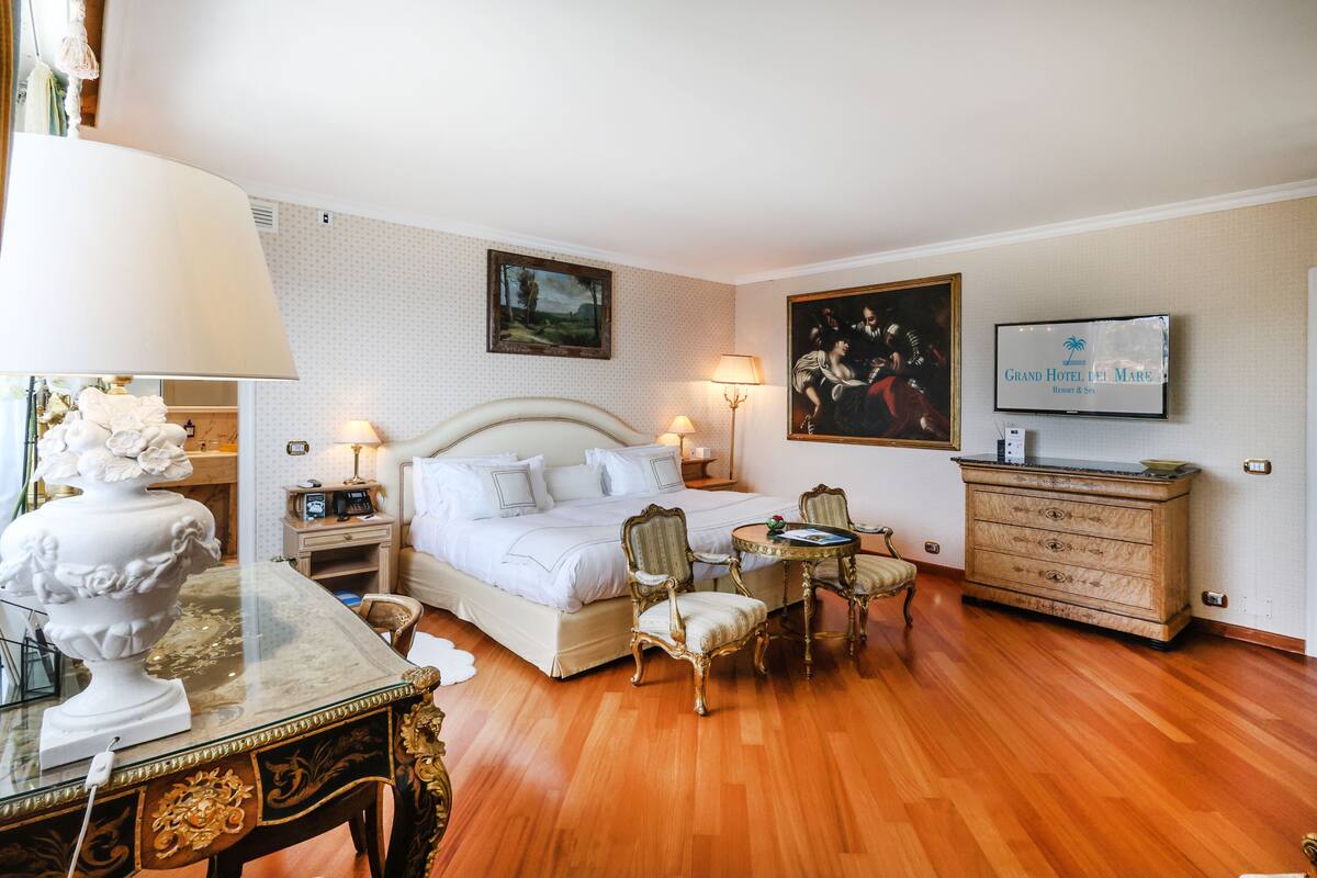 Ein Hotelzimmer mit Bett, Nachttischen, Fernseher, Schreibtisch mit Lampe und Stuhl.