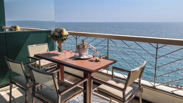 Un balcon avec une table et des chaises, donnant sur la mer.