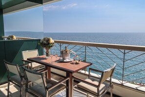 Een balkon met een tafel en stoelen, met uitzicht op de zee.