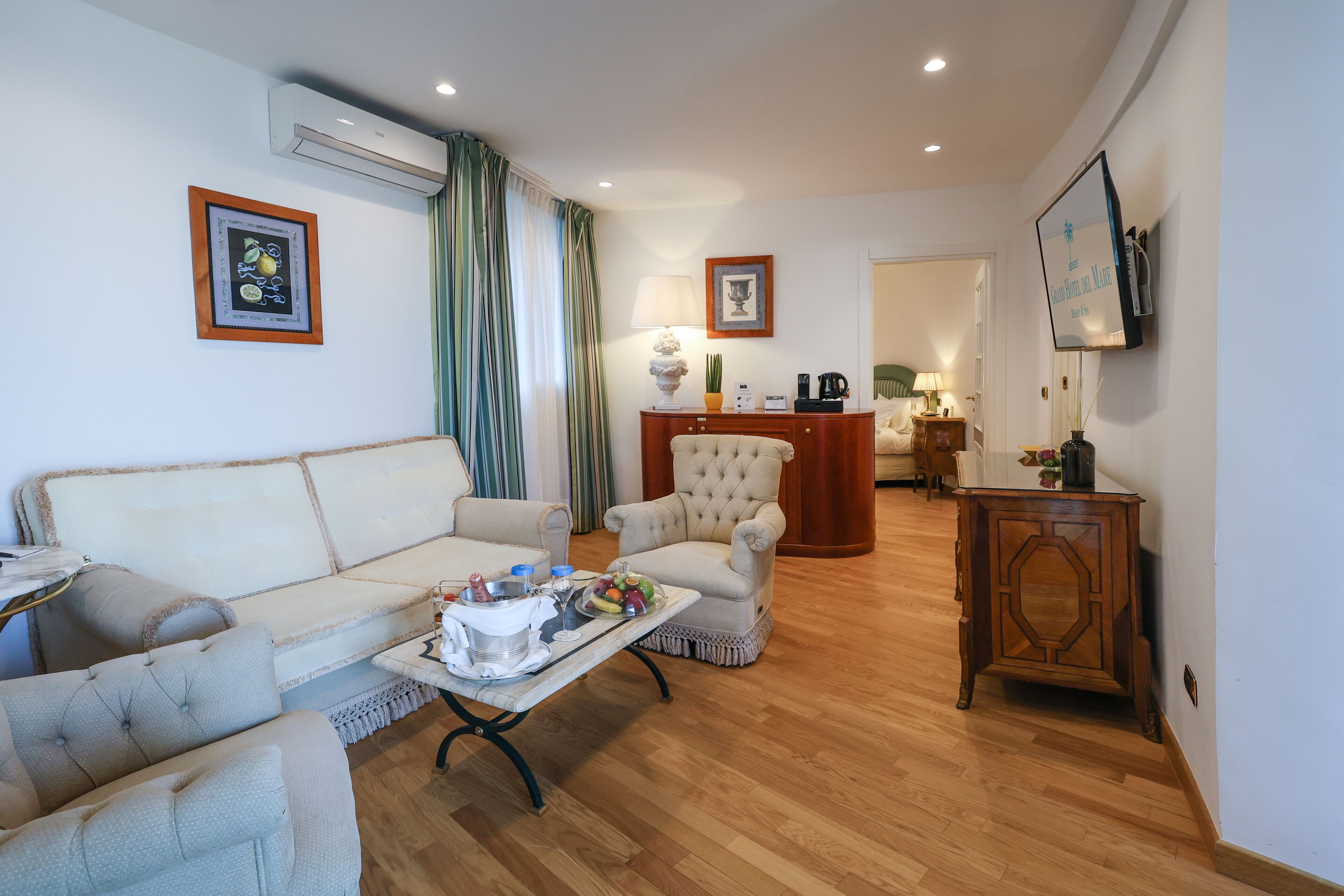 A living room with a sofa, armchair, coffee table, and a small wooden cabinet.