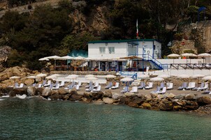 Playa privada, arena negra, sillas reclinables de playa, sombrillas