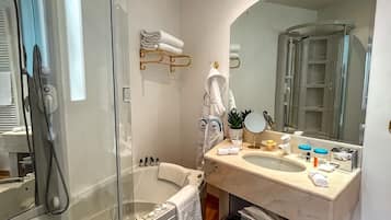 Un baño moderno con ducha de vidrio, bañera independiente, tocador con espejo grande y perchero.