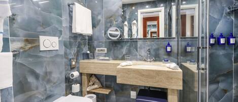 Un baño moderno con salpicadero de mármol, un lavabo con una toalla, un inodoro y una zona de ducha.