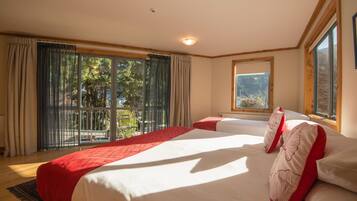 Quarto com uma cama grande, uma janela e vista para árvores.