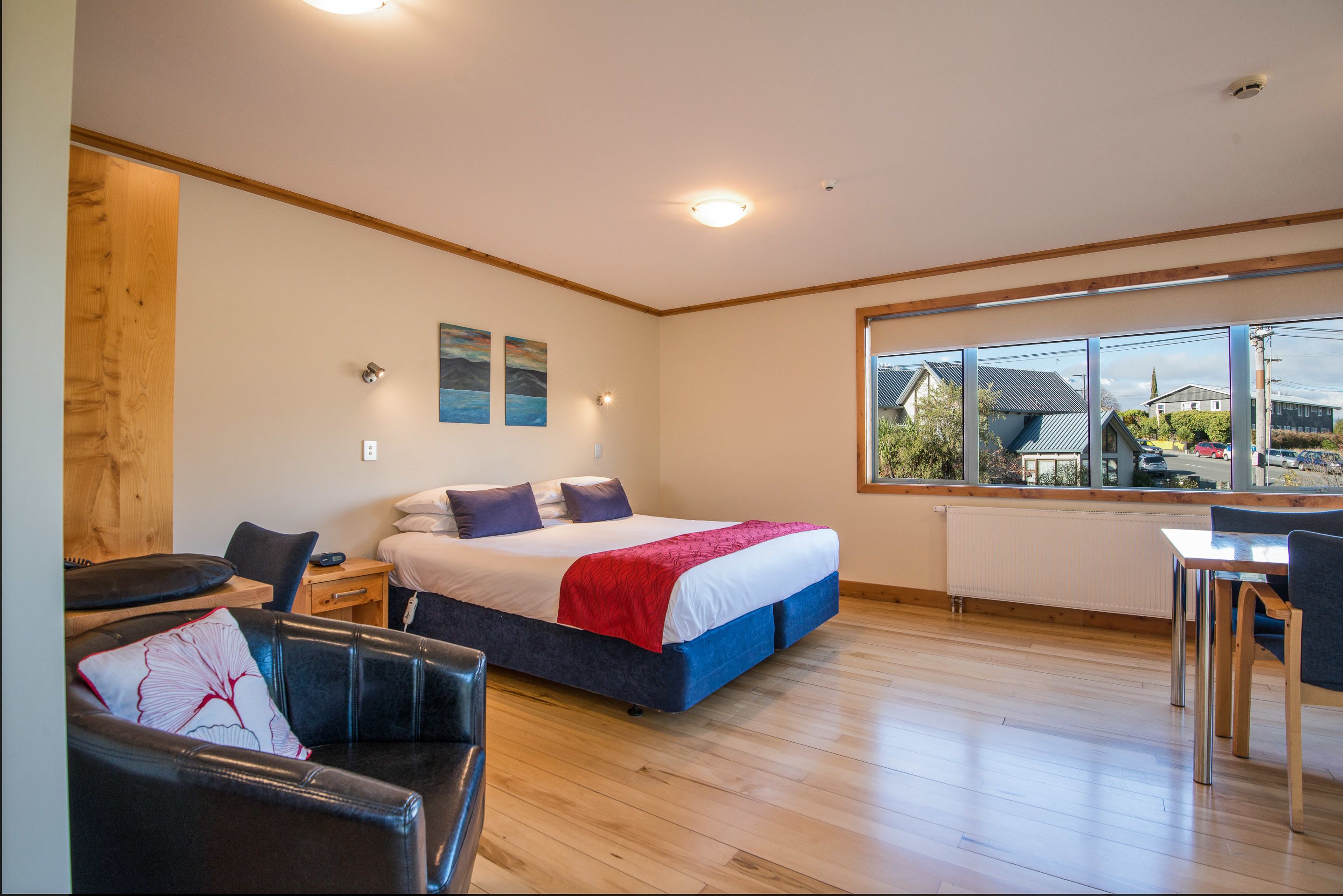 A modern room with a large bed, a desk, and a view of the outside.