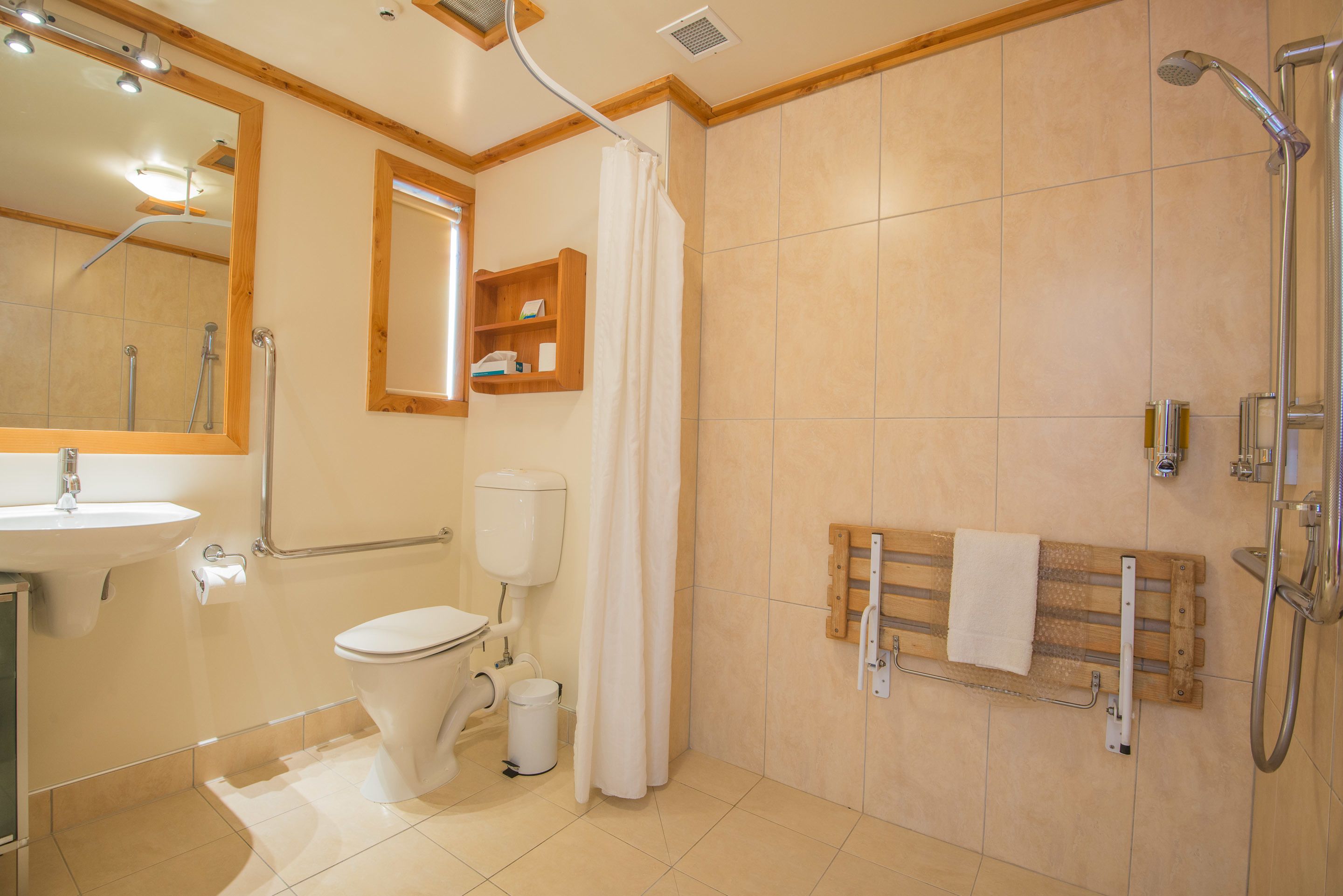 A bathroom with a toilet, sink, shower, and a towel rack.