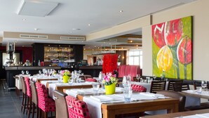 A restaurant with multiple dining tables, chairs, and a bar area. - Malpertuus (Riemst)