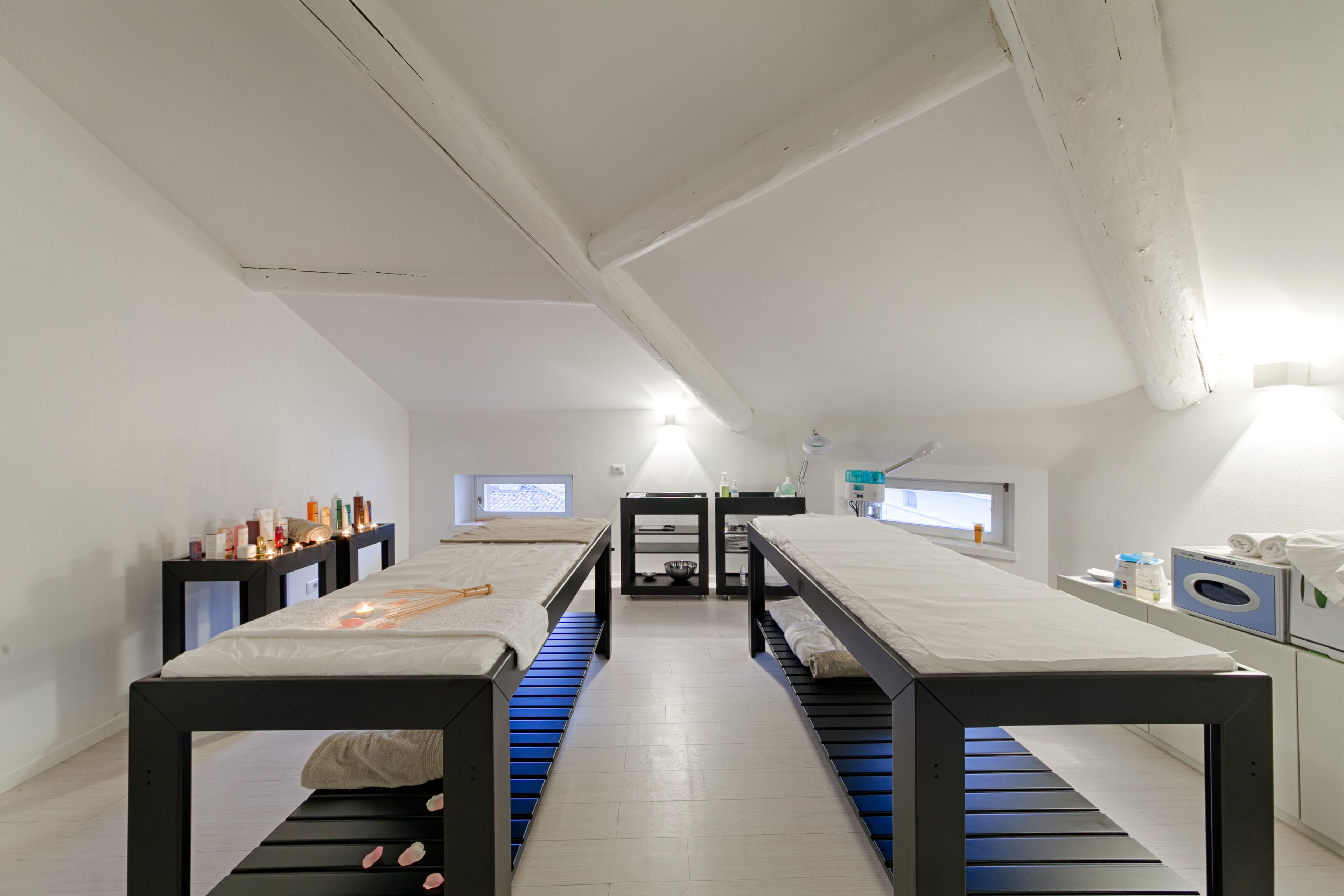 Une chambre moderne et minimaliste, avec un lit central, deux tables de chevet, une petite fenêtre et un lave-linge encastré.