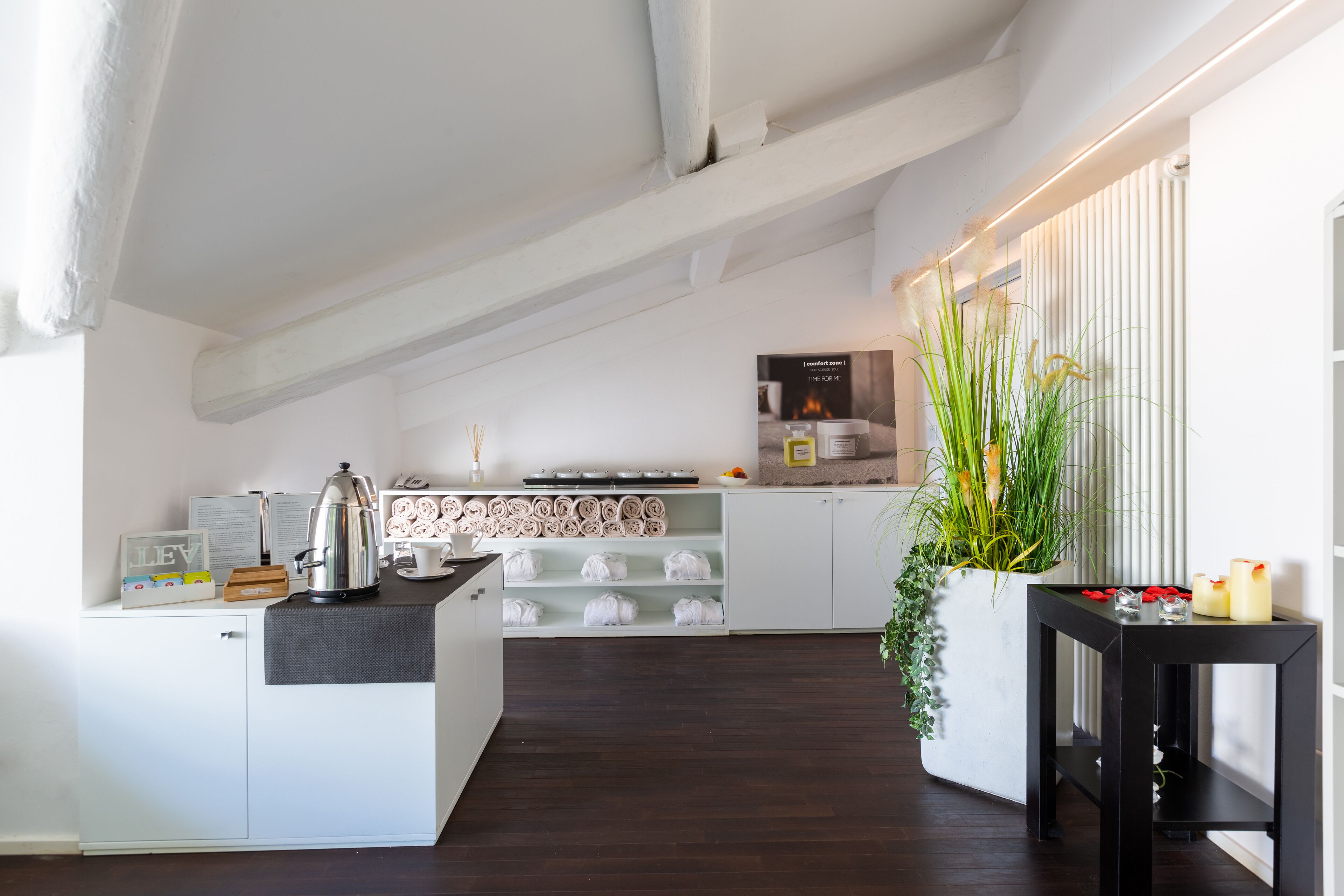 Eine moderne Küche mit weißen Schränken, einer Kaffeestation und einem schwarzen Beistelltisch mit Kerzen.